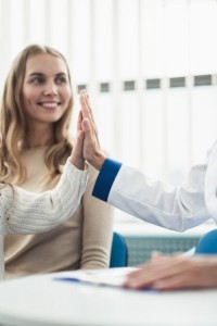 Concept of trustworthy method of consultation in healthcare system. Waist up portrait of smiling little girl giving five to pediatrician lady in medical cabinet